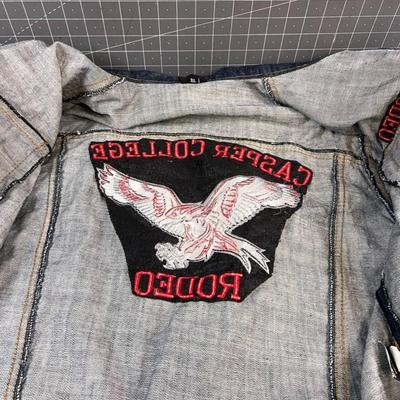 Sale Photo Thumbnail #614: This stylish denim jacket features Casper College Rodeo embroidery and a durable design, ideal for casual or western wear.

• Button-Up Front Closure
• Dual Chest Pockets With Button Flap
• Side Welt Pockets
• Embroidered Casper College Rodeo Logo