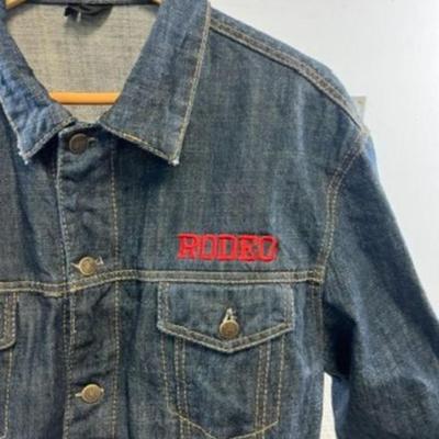 Sale Photo Thumbnail #609: This stylish denim jacket features Casper College Rodeo embroidery and a durable design, ideal for casual or western wear.

• Button-Up Front Closure
• Dual Chest Pockets With Button Flap
• Side Welt Pockets
• Embroidered Casper College Rodeo Logo