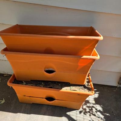 Three large orangish colored planters with tomato walls - self watering basin!