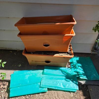Three large orangish colored planters with tomato walls - self watering basin!