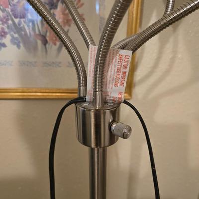 Adjustable armed floor lamp with gold framed wall art pair