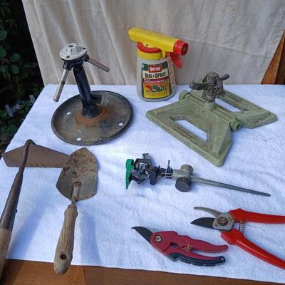 Assortment of yard sprinklers, small hand - tools, and a sprayer