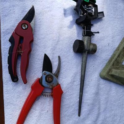 Assortment of yard sprinklers, small hand - tools, and a sprayer