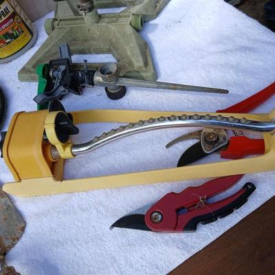 Assortment of yard sprinklers, small hand - tools, and a sprayer