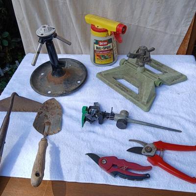 Assortment of yard sprinklers, small hand - tools, and a sprayer