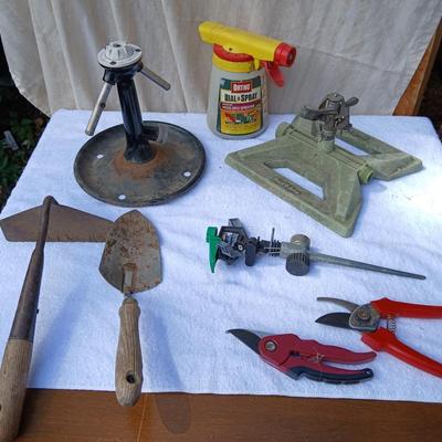 Assortment of yard sprinklers, small hand - tools, and a sprayer