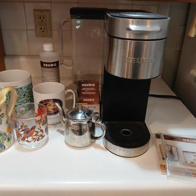 Keurig coffee pot with coffee mugs and other accessories