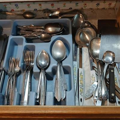 Drawer organizer full of assorted mis-matched flatware and a nice utensil set