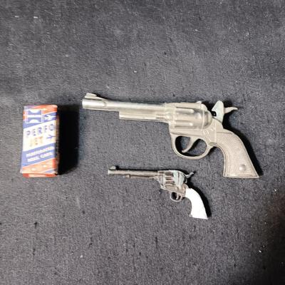 PET TOY CAP GUN WITH A BOX OF ROLLED CAPS AND A SMALLER METAL TOY GUN