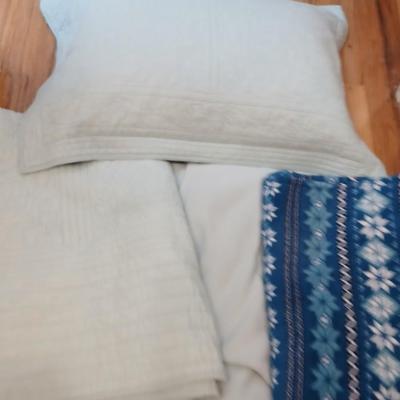 Twin sized bedspread with pillowcases with a Soft Twin blue blanket, a decorative pattern throw, and a quilted Doiley