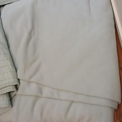 Twin sized bedspread with pillowcases with a Soft Twin blue blanket, a decorative pattern throw, and a quilted Doiley