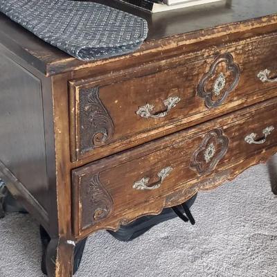 Sale Photo Thumbnail #55: A pair of side tables with some carved (applied?) designs on the front.  Not good on the finishes, but solid bones.  Approx 36" wide, 18" deep and 24" tall.