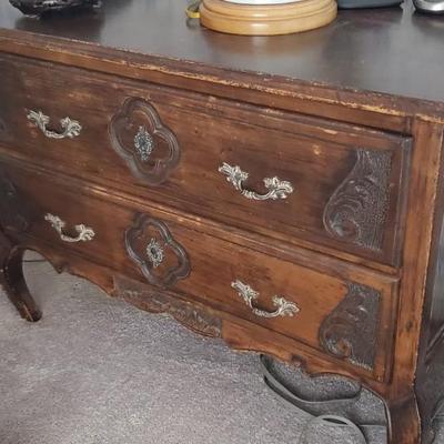Sale Photo Thumbnail #54: A pair of side tables with some carved (applied?) designs on the front.  Not good on the finishes, but solid bones.  Approx 36" wide, 18" deep and 24" tall.