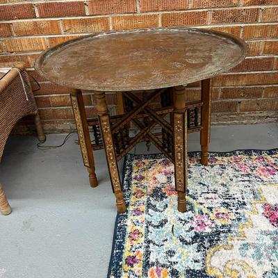 Sale Photo Thumbnail #122: Moroccan Brass Tray Top Table.  Characterized by its intricately engraved brass top and a foldable wooden base.
Approximate Measurements   26.5" Round and 20" Tall