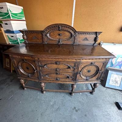 Sale Photo Thumbnail #6: Impressive antique oak sideboard featuring elaborate carved ornamentation and strong geometric motifs. The piece includes paneled oval and circular drawer/door fronts, turned legs with a stretcher base, and an arched decorative backboard with finely carve