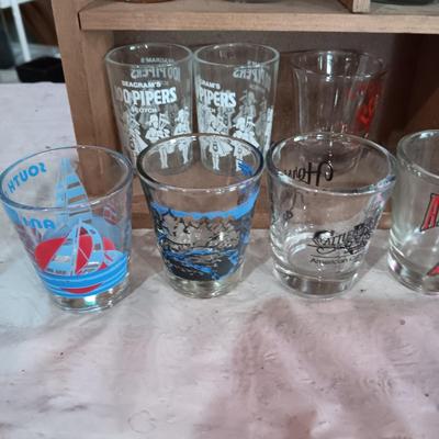 A COLLECTION OF SHOT GLASSES AND A HOUSE SHAPED WALL SHELF