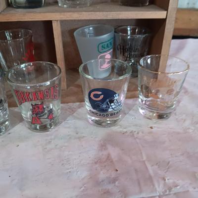 A COLLECTION OF SHOT GLASSES AND A HOUSE SHAPED WALL SHELF