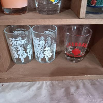 A COLLECTION OF SHOT GLASSES AND A HOUSE SHAPED WALL SHELF