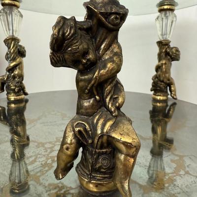 Sale Photo Thumbnail #68: Set of two matching round glass-top side tables featuring ornate gold-tone cherub supports and decorative legs. Mid-century Hollywood Regency style.