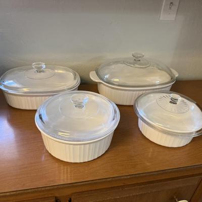 Sale Photo Thumbnail #186: Set of four classic white CorningWare casserole dishes with matching glass lids. Durable and versatile—perfect for baking, serving, and storing.