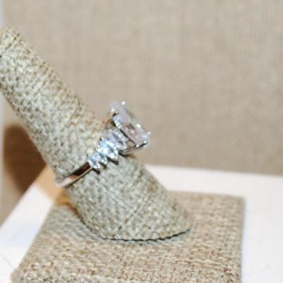 Size 8 Large Oval Clear Stone Ring with 8 Diamond Shape Side Accents on a Silver Tone Band (5.0g)