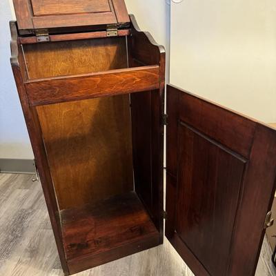 Sale Photo Thumbnail #232: Charming vintage wooden trash bin cabinet with a hinged flip-top lid and front door access. Rich wood finish with paneled detailing adds a rustic touch. Functional storage for kitchen, pantry, or laundry room use, while doubling as a decorative accent pie