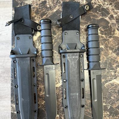 Sale Photo Thumbnail #236: KA-BAR fixed-blade fighting/utility knives, each stamped KA-BAR, Olean, NY. Classic 7-inch 1095 Cro-Van steel blades with black Kraton handles, paired with heavy-duty molded tactical sheaths and nylon belt loops. Durable, sharp, and ready for field, colle