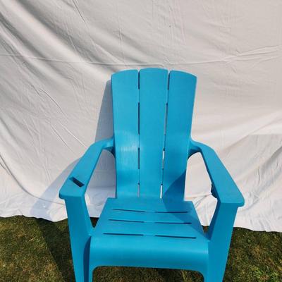 Sale Photo Thumbnail #30: Blue plastic Adirondack-style chair designed for outdoor use. Features a slatted backrest, armrests, and contoured seat for comfort. Lightweight and weather-resistant, suitable for patios or gardens. Durable construction with a classic design. In well-mai