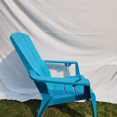 Sale Photo Thumbnail #31: Blue plastic Adirondack-style chair designed for outdoor use. Features a slatted backrest, armrests, and contoured seat for comfort. Lightweight and weather-resistant, suitable for patios or gardens. Durable construction with a classic design. In well-mai