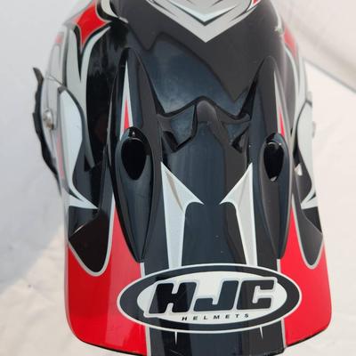 Sale Photo Thumbnail #50: HJC off-road motorcycle helmet featuring a striking red, black, and white graphic design. Includes an adjustable visor and built-in mounting points. Comes with tinted goggles for eye protection. Designed for off-road use, this helmet is lightweight and of