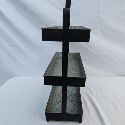 Sale Photo Thumbnail #65: Three-tier tray stand constructed from galvanized metal with a black finish and sturdy metal frame. Features a carrying handle at the top for easy portability. Suitable for kitchen, decoration, or organizational purposes. Includes three spacious rectangul