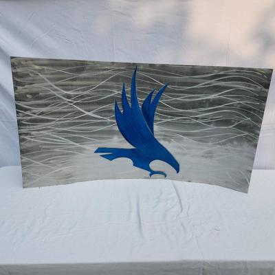 Sale Photo Thumbnail #77: A metal artwork panel featuring a blue bird design, set against a highly stylized background with wave-like silver patterns. The panel exhibits a combination of polished and painted finishes. Dimensions and artist details are unspecified. In good conditio