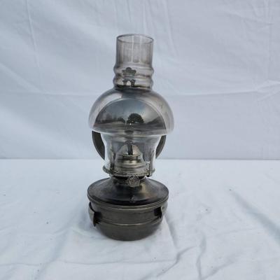 Sale Photo Thumbnail #81: Wall-mounted oil lamp featuring a metal base and a clear glass chimney with a domed design. The lamp includes a hinged metal wall bracket for mounting and a wick mechanism for functional use. Suitable for decorative or practical purposes. Dimensions and m