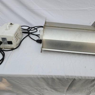 Sale Photo Thumbnail #104: Metal halide light fixture featuring a metal reflector housing, an integrated ballast unit, and a clear bulb installed. The ballast casing is white with visible signs of wear, and labeled with operational specifications. The unit includes wired connection