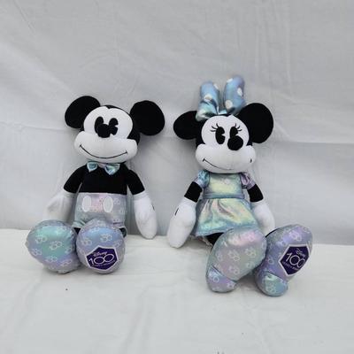Sale Photo Thumbnail #142: Plush toys featuring Mickey and Minnie Mouse, each dressed in matching iridescent outfits. Mickey wears light silver and blue accents with matching iridescent shoes, while Minnie sports an iridescent dress and bow. Both have '100' detailing on the bottom 