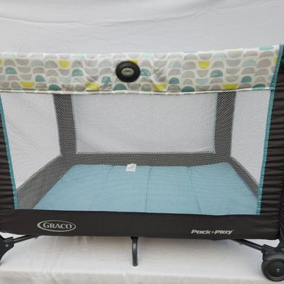 Sale Photo Thumbnail #146: Graco Pack 'n Play portable playard featuring a mesh design for easy ventilation and visibility. Includes a sturdy frame with wheels for easy mobility and a patterned fabric upper section. Comes with a convenient carrying bag for transportation and storag