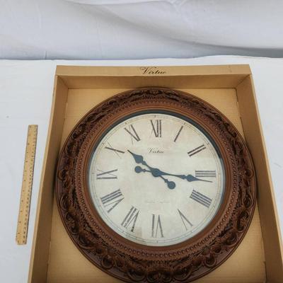 Sale Photo Thumbnail #149: Decorative wall clock featuring a vintage-style design. The clock is framed with an intricately patterned border in a wood-like finish. The face displays Roman numerals with two elegantly styled clock hands. Packaged in its original box labeled 'Decorativ