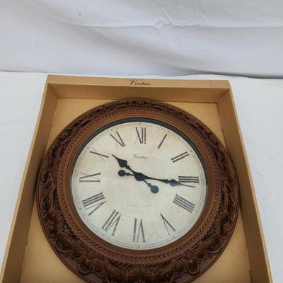 Sale Photo Thumbnail #148: Decorative wall clock featuring a vintage-style design. The clock is framed with an intricately patterned border in a wood-like finish. The face displays Roman numerals with two elegantly styled clock hands. Packaged in its original box labeled 'Decorativ