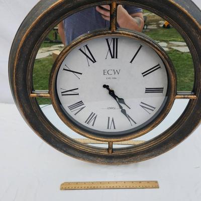 Sale Photo Thumbnail #164: K&W wall clock featuring a distressed metallic frame with an antique-style finish. The clock face displays large Roman numerals and black spade hands for easy readability. Ideal for wall mounting, the clock is battery-operated (batteries not included). No
