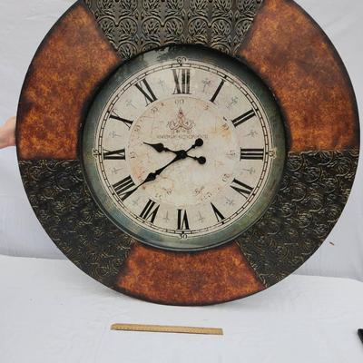 Sale Photo Thumbnail #165: Large round wall clock featuring Roman numerals on an aged-style clock face. The frame has decorative detailing and a two-tone design with textured and smooth sections. The clock has ornate hour and minute hands and is designed for wall mounting. Function