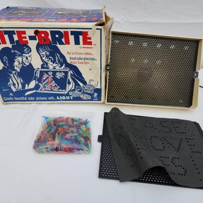 Sale Photo Thumbnail #167: Lite-Brite toy including the original box, perforated black panels, pegs in various colors, and a sample template sheet. The box shows signs of wear and age. The toy appears intact with its components. Power cord is visibly included. Condition of light fu