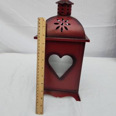 Sale Photo Thumbnail #173: Red metal decorative lantern featuring heart-shaped cutouts on the door and sides. The lantern includes a hinged door for easy access and has a domed top with floral perforations for ventilation. It stands upright on four small feet and includes a ring at