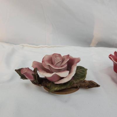 Sale Photo Thumbnail #195: Two ceramic rose figurines, including a pink rose with green leaf details on a base and a red rose with white accent edges. Both are highly detailed. The ruler indicates approximate size, with each piece under 6 inches in width. Condition appears intact w