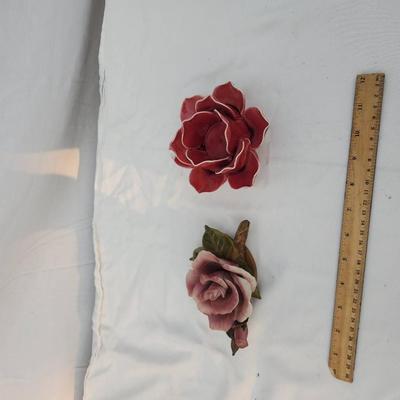 Sale Photo Thumbnail #194: Two ceramic rose figurines, including a pink rose with green leaf details on a base and a red rose with white accent edges. Both are highly detailed. The ruler indicates approximate size, with each piece under 6 inches in width. Condition appears intact w