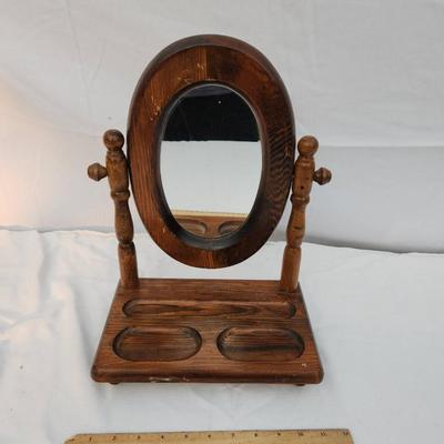 Sale Photo Thumbnail #196: Wooden vanity mirror featuring an oval frame mounted on two turned posts. The base includes a recessed tray section with three distinct compartments for small items. The piece is freestanding and measures approximately as indicated by the ruler for scale.