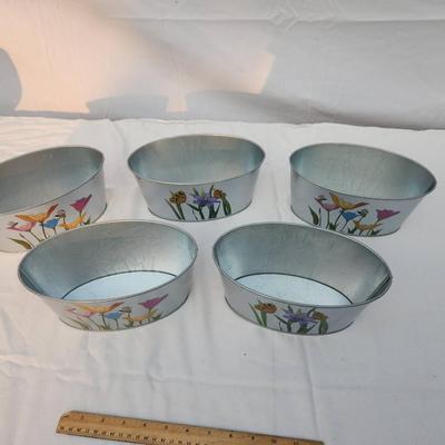 Sale Photo Thumbnail #199: 5 oval-shaped metal planters featuring colorful hand-painted floral designs accented with butterflies and bees. Each planter is approximately 10 inches wide, as indicated by the ruler in the image. These lightweight planters are ideal for indoor or outdoo