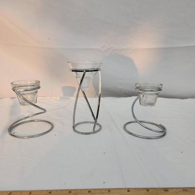 Sale Photo Thumbnail #204: Three modern candle holders with a chrome-like metal spiral design. Each features a removable clear glass insert to accommodate candles. The sizes vary, creating a tiered presentation. Suitable for different candle sizes. The largest holder has a height o