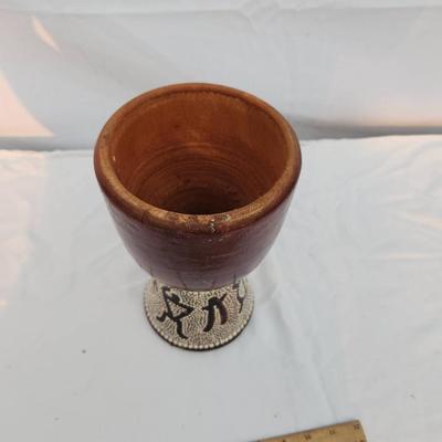 Sale Photo Thumbnail #210: A handcrafted wooden goblet featuring a smooth wooden bowl and a beaded base adorned with decorative patterns. The intricate beadwork showcases figures and geometric designs, adding a striking detail. The goblet shows signs of prior use, with visible wear