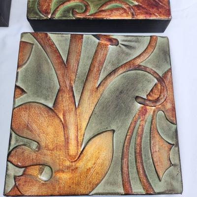 Sale Photo Thumbnail #213: Nine decorative wall tiles with embossed floral motifs in various earth-tone colors including green, orange, and bronze. Each tile is square-shaped and made primarily of durable material, potentially ceramic or resin. The carved and painted surface create