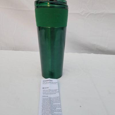 Sale Photo Thumbnail #233: A green stainless steel insulated travel tumbler with a matching lid. Designed for maintaining beverage temperatures. Includes an instruction or care sheet. The tumbler features a stainless steel interior and a green exterior with a silicone grip band for
